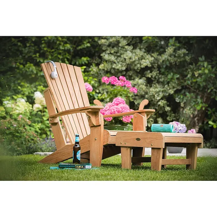 Kai Wiechmann Gartenhocker - Teakholz, Klappbar, braun - Hölzerner Adirondack-Stuhl und passende Fußstütze in einem Garten.