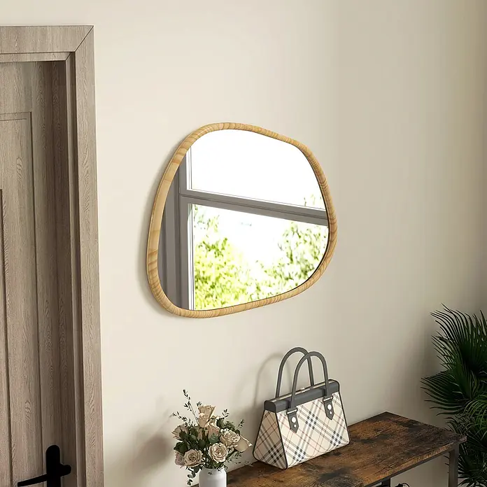 Homcom Wandspiegel - 2 x 50 cm, Naturholz - Ein unregelmäßig geformter Spiegel mit hellem Holzrahmen hängt an einer cremefarbenen Wand im Eingangsbereich und reflektiert ein Fenster mit grünem Laub.