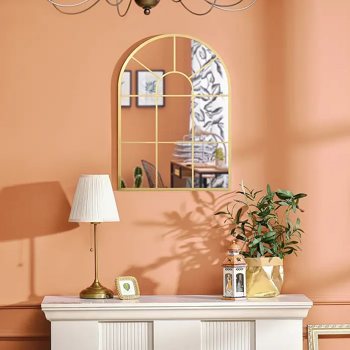 Homcom Wandspiegel - Gold - Goldgerahmter Bogen-Spiegel mit Gitterdetails, der einen Innenraum reflektiert, an einer pfirsichfarbenen Wand hängend.