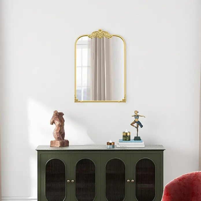 Homcom Wandspiegel - Gold - Goldener Bogenspiegel mit Zierakzenten oben und an den Ecken, der ein Fenster reflektiert. Über einem dunkelgrünen Schrank mit Deko montiert.