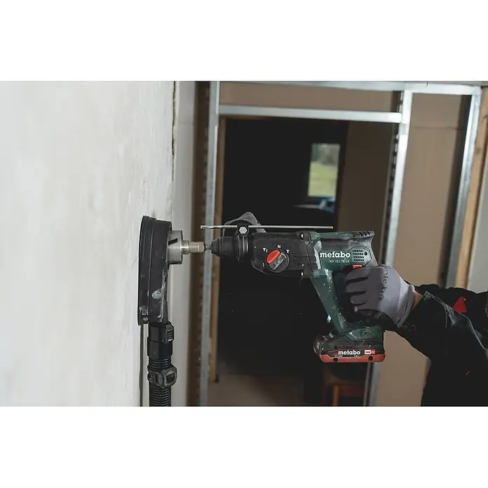 Metabo CAS 18V Akku-Kombihammer KH 18 LTX 24 - 18 V, Ohne Akku, 2,1 J - Grüner und schwarzer Metabo Bohrhammer mit Staubabsaugung bohrt in eine helle Wand, gehalten von einer behandschuhten Hand.