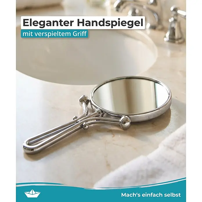 Calmwaters Kosmetikspiegel - Durchmesser: 12,7 cm, Rund, Chrom, Vergrößerung 1: 500 % - Eleganter silberner Handspiegel mit verspieltem Griff, auf einer Waschtischplatte neben einem Waschbecken.