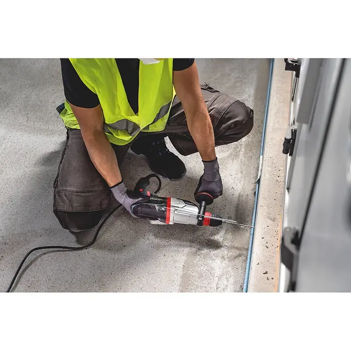 Metabo Kombihammer KHE 2860 - 880 W, 3,2 J, SDS-Plus-Aufnahme - Arbeiter in Warnweste bedient Metabo Bohrhammer auf Betonoberfläche.