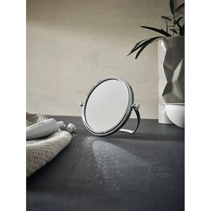 Calmwaters Kosmetikspiegel - Durchmesser: 13,9 cm, Rund, Chrom, Vergrößerung 1: 500 % - Silberner Kosmetikspiegel auf dunkler Oberfläche, umgeben von Pflegeprodukten und einer Pflanze.