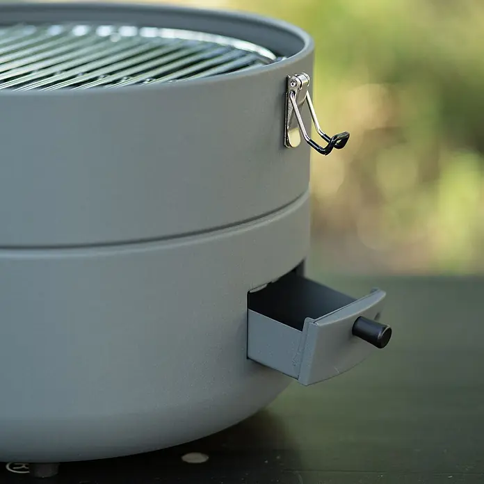TAINO Gasgrill To-Go - 2,5 kW, Anzahl Brenner: 1 Stk. - Grauer tragbarer Grill mit sichtbarem Metallrost, seitlichem Griff und ausziehbarer Ascheschublade.