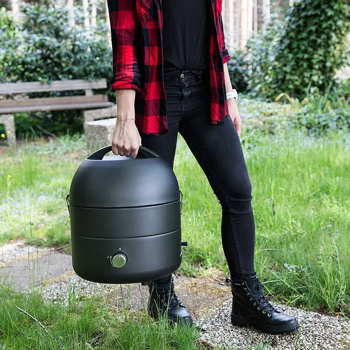 TAINO Gasgrill To-Go - 2,5 kW, Anzahl Brenner: 1 Stk. - Dunkelgrauer, portabler Grill mit mattem Finish und Tragegriff, von einer Person im Freien getragen.