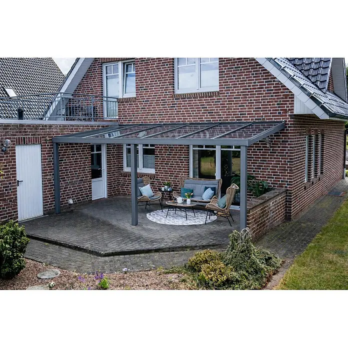 Gardendreams Terrassenüberdachung Elegance - B x T: 600 x 405,5 cm, Graualuminium, Verbundsicherheitsglas (VSG), Klar - Graue Terrassenüberdachung mit transparentem Dach, an Backsteinhaus montiert, beschattet einen Sitzbereich.