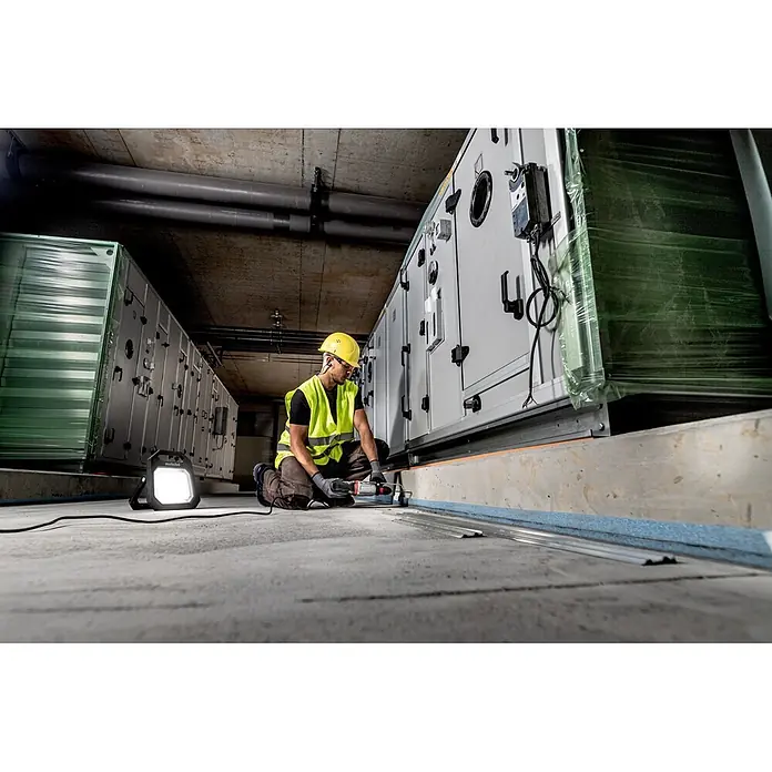 Metabo Kombihammer KHE 2860 - 880 W, 3,2 J, SDS-Plus-Aufnahme - Arbeiter in Schutzkleidung bohrt mit einem Metabo Bohrhammer in Betonboden neben großen Maschinen, beleuchtet von einer Arbeitsleuchte.