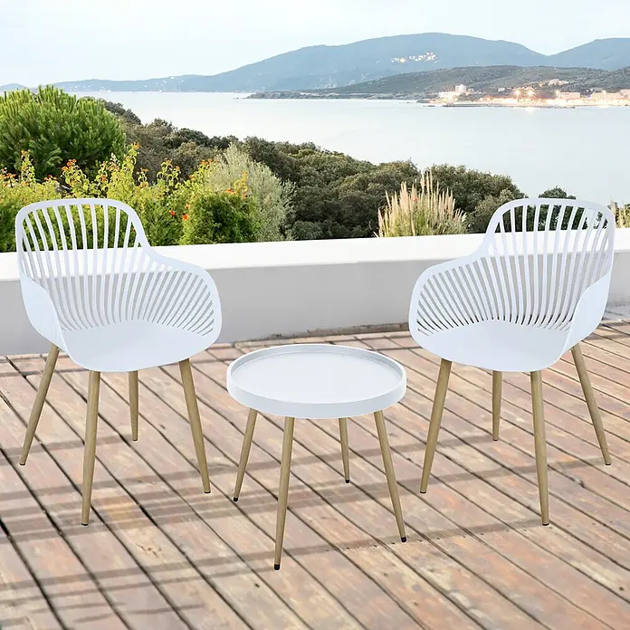 SVITA Gartenstuhl-Set - Weiß - Weißes Outdoor-Set mit zwei Stühlen und einem runden Tisch mit Holzbeinen auf einer Holzterrasse mit Meerblick.