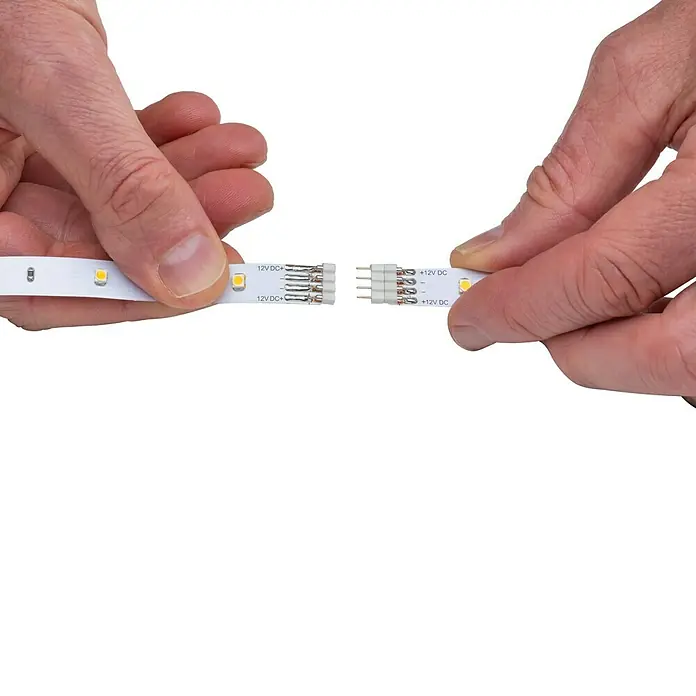 Paulmann LED-Band YourLED Eco Basisset - 3 m, Warmweiß - LED-Streifen werden von Händen mit einem Verbinder zusammengeführt. Das Produkt wird für Beleuchtungszwecke verwendet.