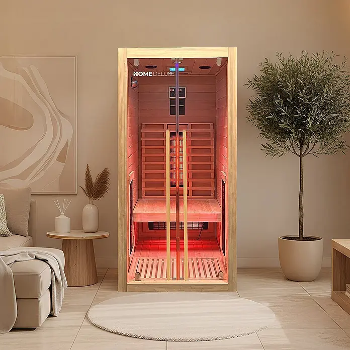 Home Deluxe Elementsauna SONORA S - Sonstige, Steuerung Ofen: Integriert, L x B x H: 90 x 90 x 190 cm - Eine moderne Infrarotsauna aus hellem Holz mit rot leuchtendem Inneren, platziert in einem zeitgenössischen Wohnzimmer.