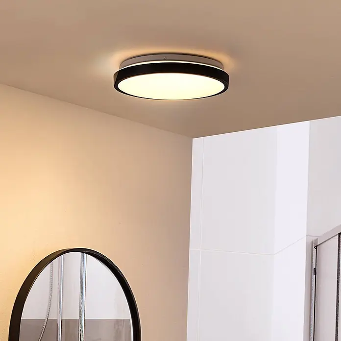 Lindby Deckenleuchte Medon - schwarz - Runde schwarz-weiße LED-Deckenleuchte an der Decke, die einen modernen Raum mit hellen Wänden warm beleuchtet.