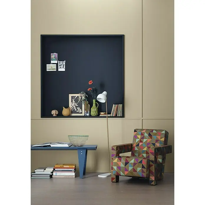 SCHÖNER WOHNEN-Farbe Wandfarbe Trendfarbe - Moon, Matt, 1 l, Konservierungsmittelfrei - Einrichtungsidee mit einem auffälligen Sessel mit geometrischem Muster, einer blauen Bank und einem schwarzen Wandregal mit Deko-Objekten.
