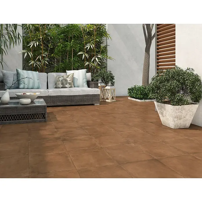 Pavimento porcelánico Lucena - 33,3 x 33,3 cm, Marrón, Mate - Azulejos cuadrados de color terracota que cubren un patio exterior, visibles como el suelo principal de una amplia zona de estar.