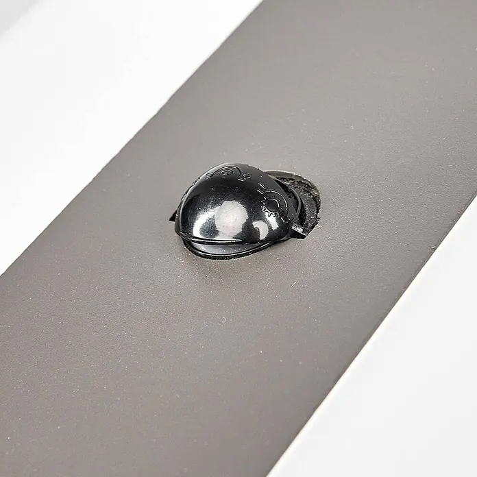 Lindby Außenwandleuchte Kumi - alu / grau / zink, IP44 - Schwarze glänzende, kuppelförmige Kunststoffkappe in eine graue strukturierte Oberfläche eingelassen.