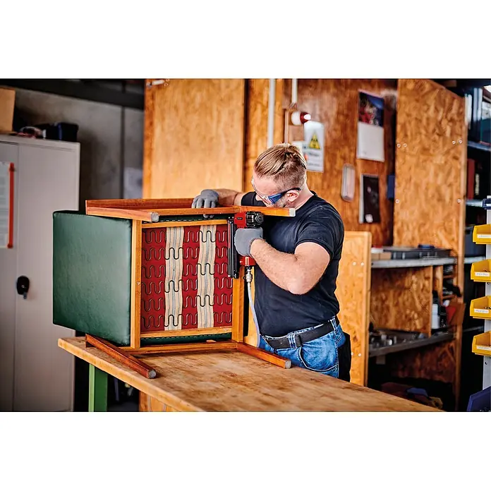 Einhell Expert Plus Flüsterkompressor TE-AC 6 Silent - Max. Druck: 8 bar, 6 l - Mann polstert einen Holzstuhlrahmen mit einem roten Tacker.