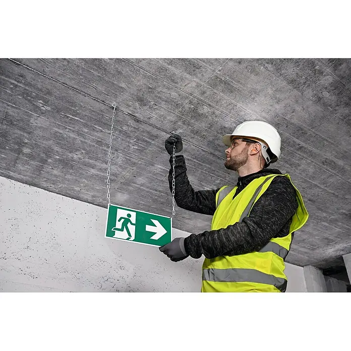 Bosch Professional Deckenhaken PRO FMH - 100 Stk. - Arbeiter installiert ein grünes Notausgangsschild mit laufender Figur und Pfeil, hängt es mit Ketten an einer Betondecke auf.