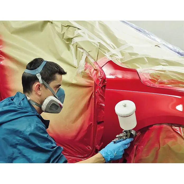 Einhell Expert Plus Flüsterkompressor TE-AC 50 Silent - Max. Druck: 8 bar, 50 l - Mann mit Atemschutzmaske und blauer Arbeitskleidung lackiert ein rotes Auto mit einer Spritzpistole.