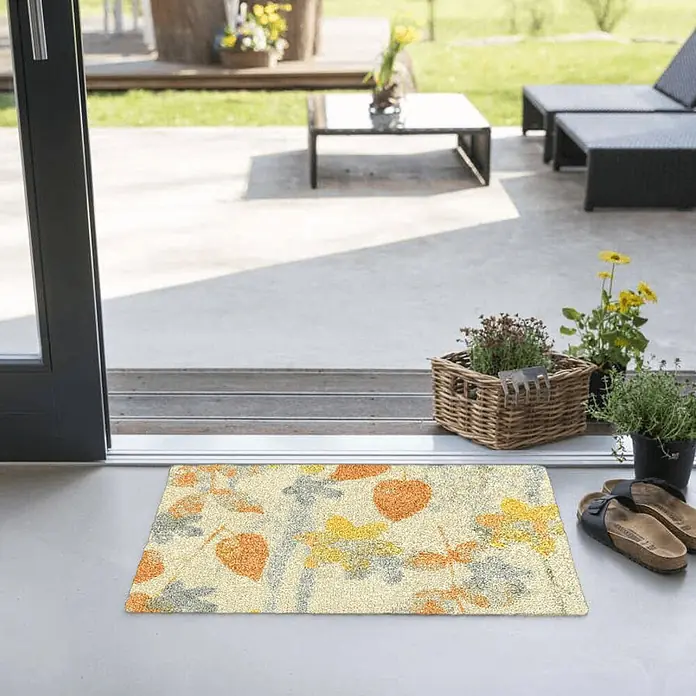 Akzente Fußmatte Feel - Mehrfarbig, Motiv / Muster|Floral - Rechteckige Fußmatte mit Herbstlaubmuster in Orange, Gelb und Grau auf hellem Hintergrund, an einer Terrassentür platziert.