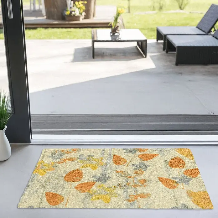 Akzente Fußmatte Feel - Mehrfarbig, Motiv / Muster|Floral - Eine herbstliche Fußmatte mit orangefarbenen, gelben und grauen Blattmustern auf beigem Hintergrund, vor einer Terrassentür platziert.