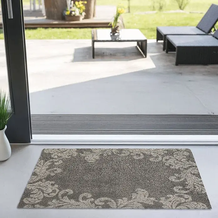 Akzente Fußmatte Feel - Mehrfarbig, Motiv / Muster|Floral - Graue Fußmatte mit verziertem Rand vor einer Terrassentür.