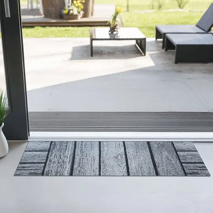 Akzente Fußmatte Feel - Mehrfarbig, Holz-Optik - Graue und schwarze Fußmatte mit Holzbretternmuster am Terrasseneingang.