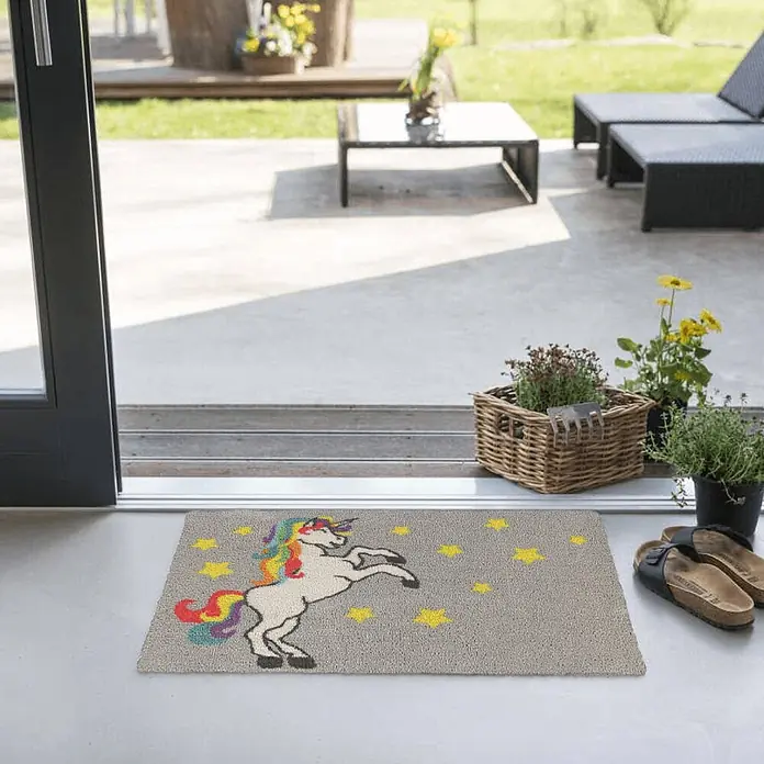 Akzente Fußmatte Feel - Mehrfarbig, Motiv / Muster|Tiere - Graue Fußmatte mit farbigem, steigendem Einhorn und gelben Sternen am Terrasseneingang.