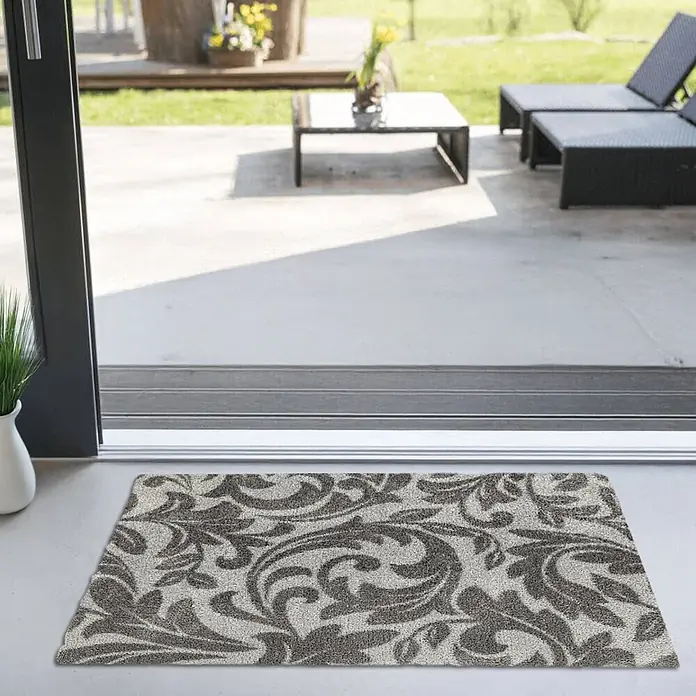 Akzente Fußmatte Feel - 100 x 70 cm, Mehrfarbig, Motiv / Muster|Floral - Beige-braun gemusterte Fußmatte auf hellem Boden, sichtbar durch eine Glasschiebetür, die zu einer Terrasse führt.