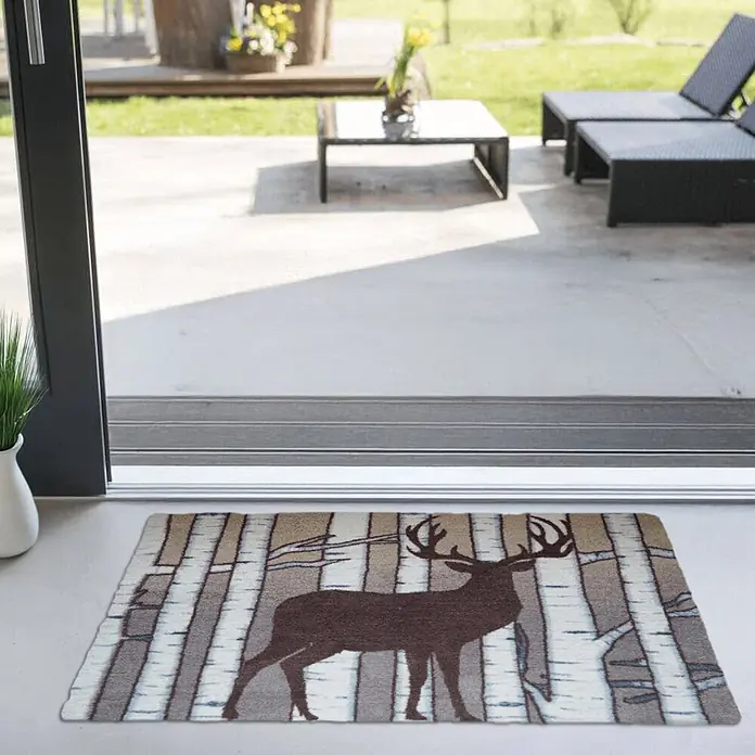 Akzente Fußmatte Feel - Mehrfarbig, Tiere - Rechteckige Fußmatte mit braunem Hirsch und Birkenbaum-Muster, vor einer Terrassentür platziert.