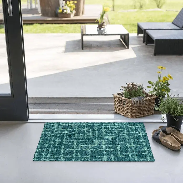 Akzente Fußmatte Feel - Mehrfarbig, Motiv / Muster - Türkis-blauer Fußabtreter mit hellem Gittermuster, an einer Terrassentür mit Pflanzen und Sandalen, für Innen- und Außenbereich.