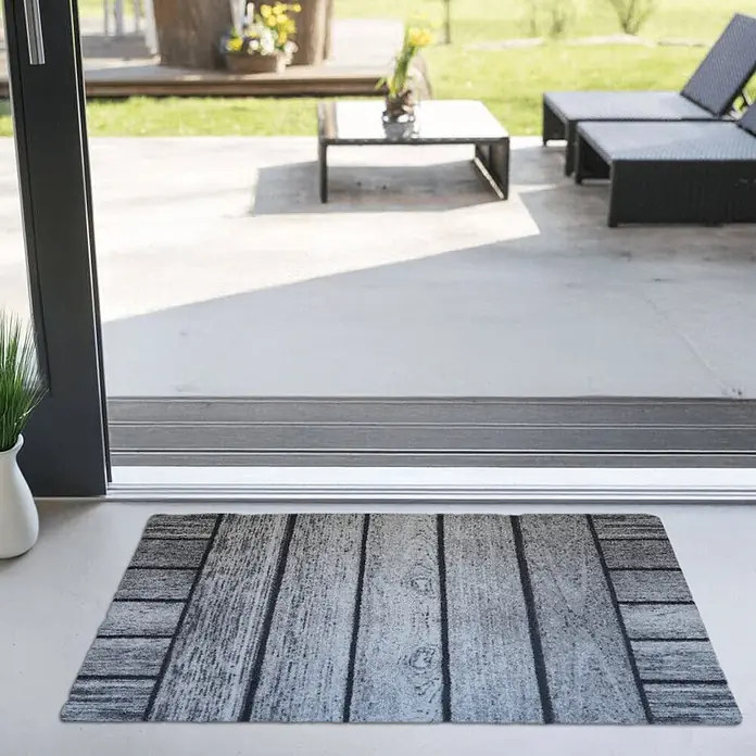 Akzente Fußmatte Feel - Mehrfarbig, Holz-Optik - Graue Fußmatte mit Holzplankenmuster an einer Terrassentür, die zu einem Außenbereich führt.