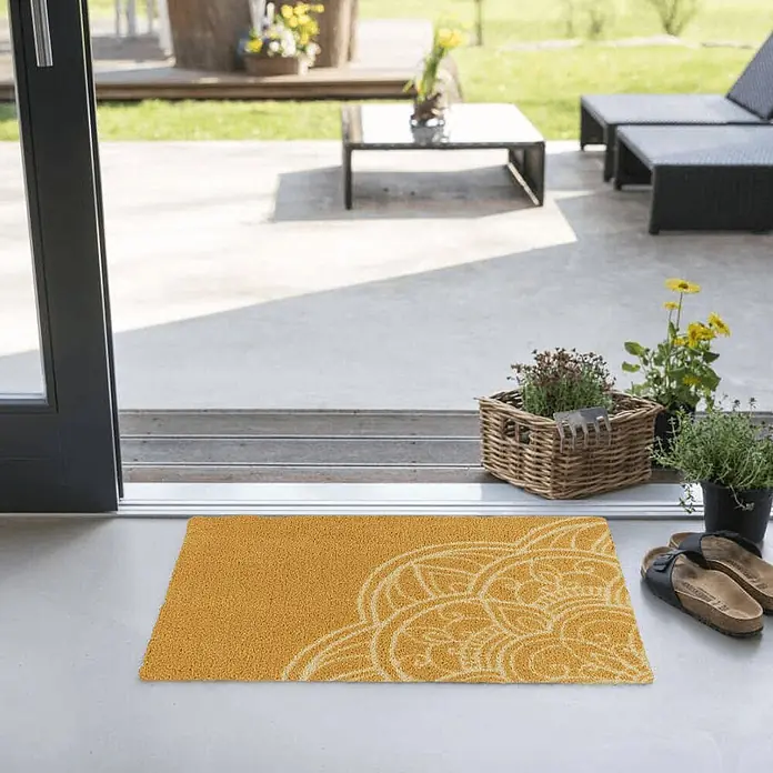 Akzente Fußmatte Feel - Mehrfarbig, Motiv / Muster - Eine strukturierte goldene Fußmatte mit einem cremefarbenen Ziermuster am Terrasseneingang.