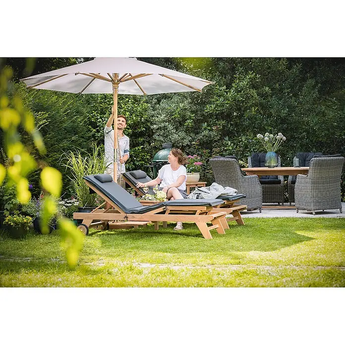 Schutzhülle Sonnenschirm 215 cm für Schirme bis d= 3,5 Universal -  - Ein Mann justiert einen großen weißen Sonnenschirm über Holzliegen mit dunklen Auflagen und einer Gartenmöbelgruppe.