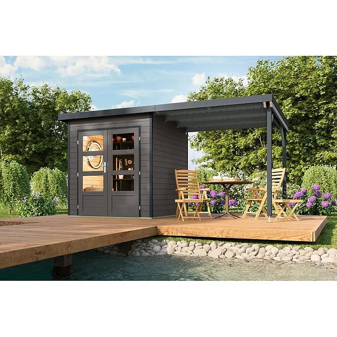 Karibu Gartenhaus Pluto 1 B - Außenmaß inkl. Dachüberstand (B x T): 447 x 228 cm, Holz, Terragrau/Anthrazit - Dunkelgraues Gartenhaus mit Pergola auf Holzterrasse am Teich, mit Gartenmöbeln. Werkzeuge innen sichtbar.