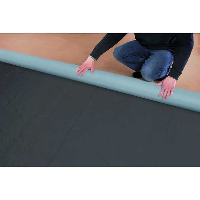 Karibu Bitumendachbahn - Elastomerbitumen, Anthrazit, 5 m² - Schwarze und blaue Schutzfolie wird von einer Person ausgerollt.