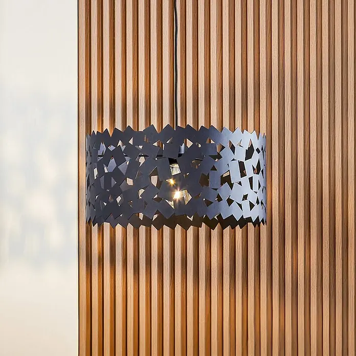 Lucande Pendelleuchte Aeloria - L x B x H: 45 x 45 x 22,5 cm, schwarz, Schwarz, E27 - Dunkelgraue Metall-Pendelleuchte mit kunstvollen Aussparungen, beleuchtet vor einer Holzlamellenwand.