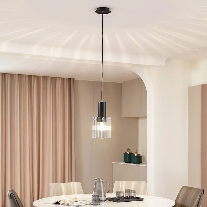Lucande Pendelleuchte Eirian - klar / transparent, klar, Schwarz, E27 - Schwarze Pendelleuchte aus geriffeltem Klarglas über einem Esstisch in einem modernen Esszimmer.