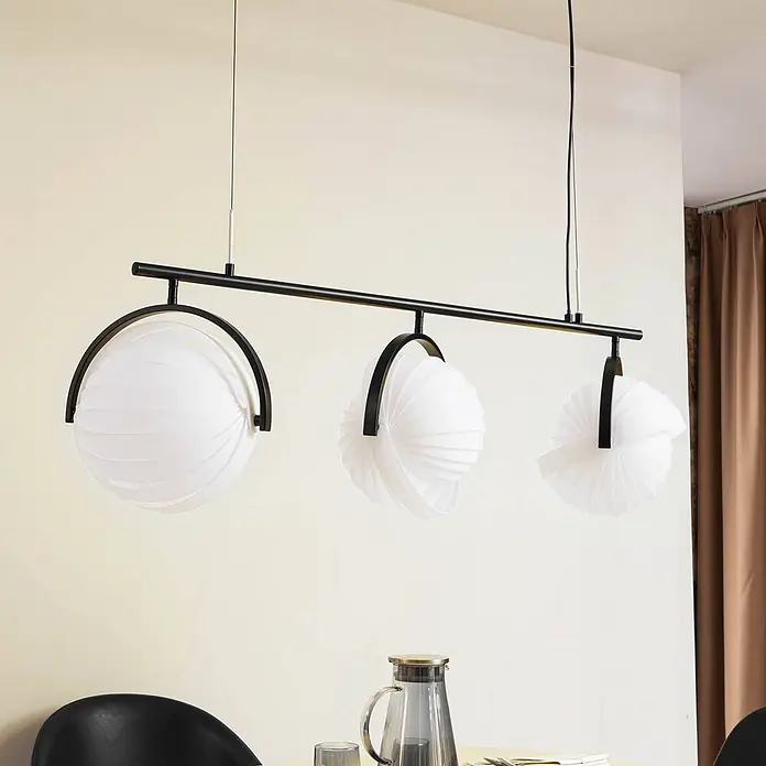 Lucande Pendelleuchte Helva - L x B x H: 120 x 32 x 27 cm, weiß / opal, weiß, Schwarz, E27 - Schwarze Metall-Pendelleuchte mit drei weißen plissierten kugelförmigen Schirmen, über einem Esstisch.
