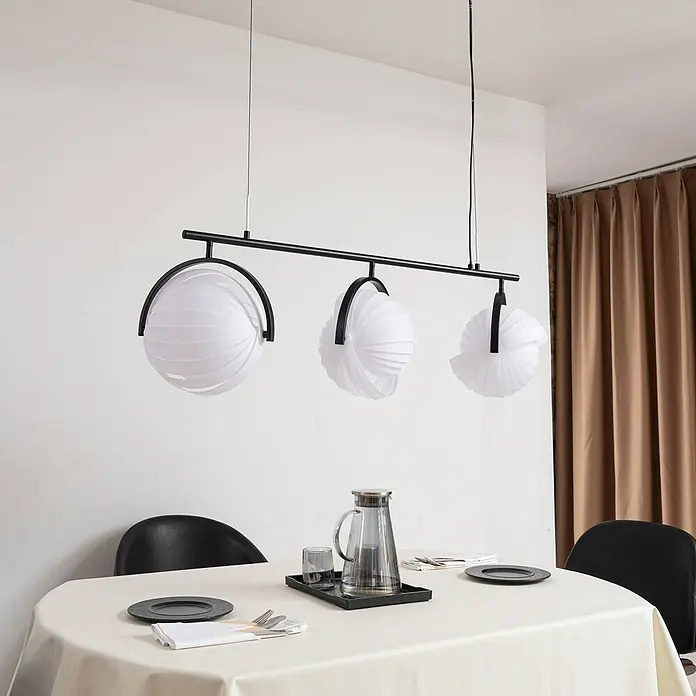 Lucande Pendelleuchte Helva - L x B x H: 120 x 32 x 27 cm, weiß / opal, weiß, Schwarz, E27 - Schwarze Pendelleuchte mit drei kugelförmigen, weißen plissierten Stoffschirmen über einem Esstisch.