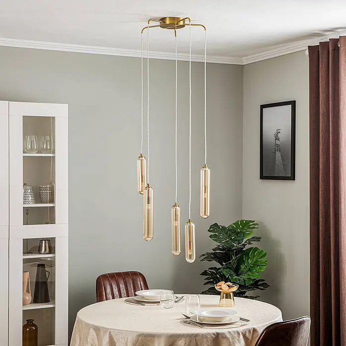 Lucande Pendelleuchte Freylin - L x B x H: 48 x 48 x 170 cm, creme / amber, amber, messing, G9 - Moderne Mehrfach-Pendelleuchte mit bernsteinfarbenen Glasrohren und einer Messing-Deckenhalterung, über einem Esstisch.