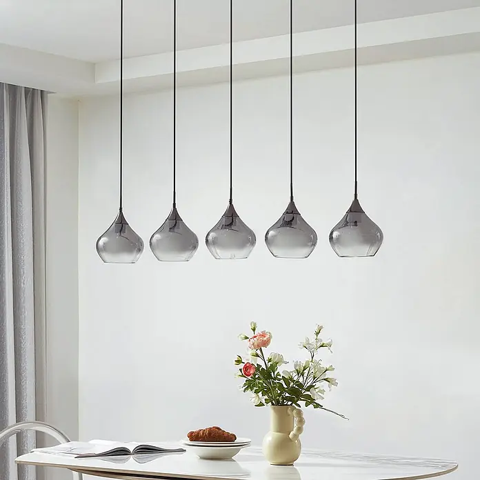 Lucande Pendelleuchte Jarven - alu / grau / zink, rauchgrau, Schwarz, E27 - Fünf tropfenförmige Pendelleuchten aus Rauchglas hängen elegant über einem Esstisch.