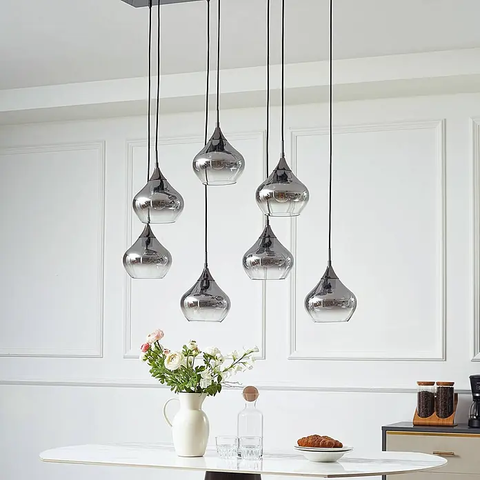 Lucande Pendelleuchte Jarven - alu / grau / zink, rauchgrau, Schwarz, E27 - Sieben chromfarbene Glas-Pendelleuchten mit tropfenförmigen Schirmen hängen von einer rechteckigen Halterung über einem Esstisch.