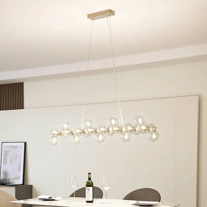 Lucande Pendelleuchte Naelen - L x B x H: 125 x 24,5 x 20 cm, creme / amber, gold, cognac, G9 - Elegante lineare Hängelampe mit mehreren klaren Glaskugeln und goldenen Akzenten über einem Esstisch.
