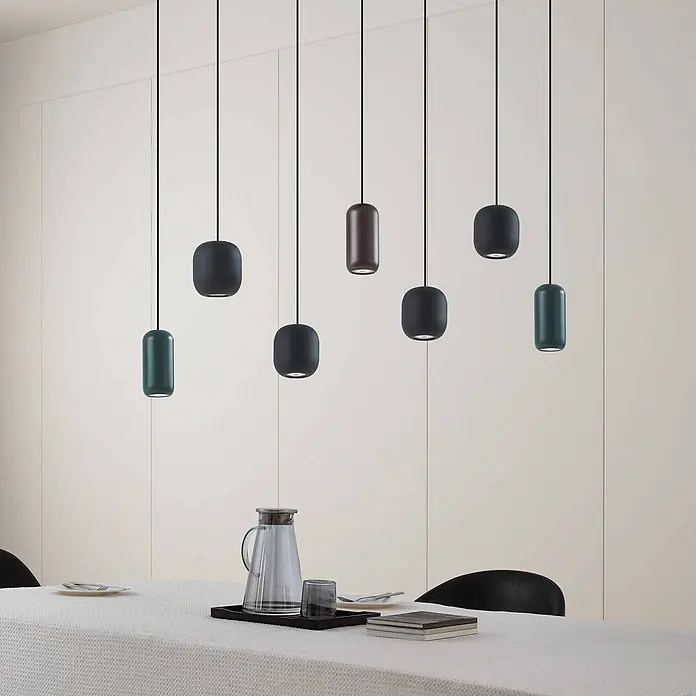 Lucande Pendelleuchte in schwarz, bunt, Hängelampe -  - Verschiedene moderne Pendelleuchten in Dunkelgrau, Braun und Dunkeltürkis über einem Esstisch.