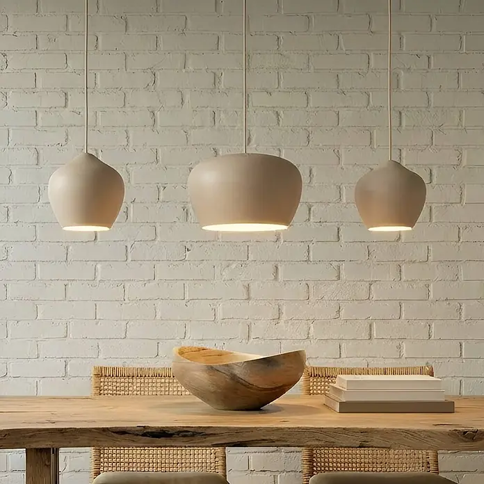 Lucande Pendelleuchte Malisa - L x B x H: 101,5 x 30 x 20 cm, creme / amber, beige, weiß, E27 - Drei beigefarbene, matte Pendelleuchten in unterschiedlichen Glockenformen hängen über einem rustikalen Holztisch.