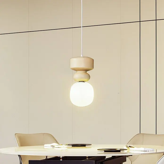 Lucande Pendelleuchte Fidelo - weiß / opal, weiß, gelb (Pantone 13-1308TXC), E14 - Eine moderne beigefarbene Pendelleuchte mit einer weiß leuchtenden Kugel hängt über einem Esstisch und beleuchtet den Raum.