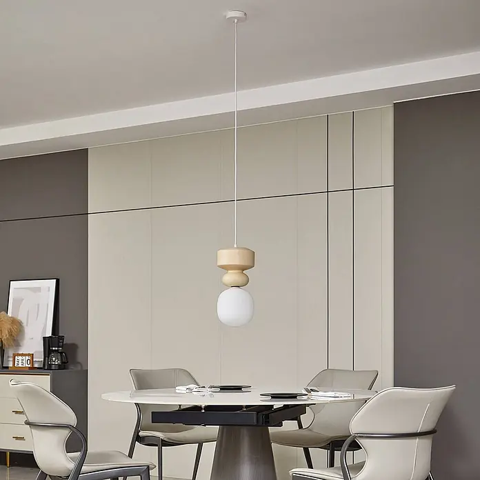 Lucande Pendelleuchte Fidelo - weiß / opal, weiß, gelb (Pantone 13-1308TXC), E14 - Pendelleuchte mit hellen Holzdetails und einem weißen, kugelförmigen Glasschirm, über einem Esstisch hängend.