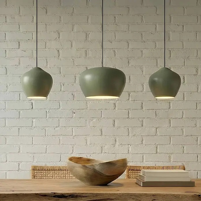 Lucande Pendelleuchte Malisa - L x B x H: 101,5 x 30 x 20 cm, grün, hellGrün, weiß, E27 - Drei salbeigrüne Pendelleuchten beleuchten einen Holztisch.