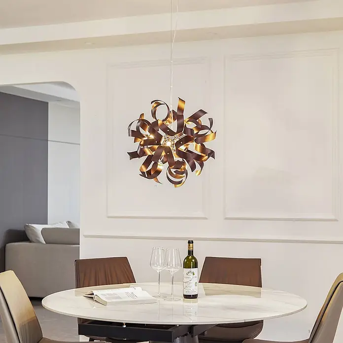 Lucande Pendelleuchte Kaelor - L x B x H: 46 x 46 x 46 cm, kupfer, satin Kupfer, G9 - Eine moderne Pendelleuchte mit verdrehten braunen und goldfarbenen Metallbändern, die einen Esstisch beleuchtet.