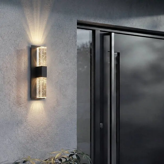 Lucande LED Wandleuchte aussen in anthrazit, transparent, Aussenlampe Wand -  - Moderne zweifache Außenwandleuchte mit blasengefüllten Diffusoren, die Licht nach oben und unten auf eine strukturierte Wand neben einer dunklen Tür wirft.